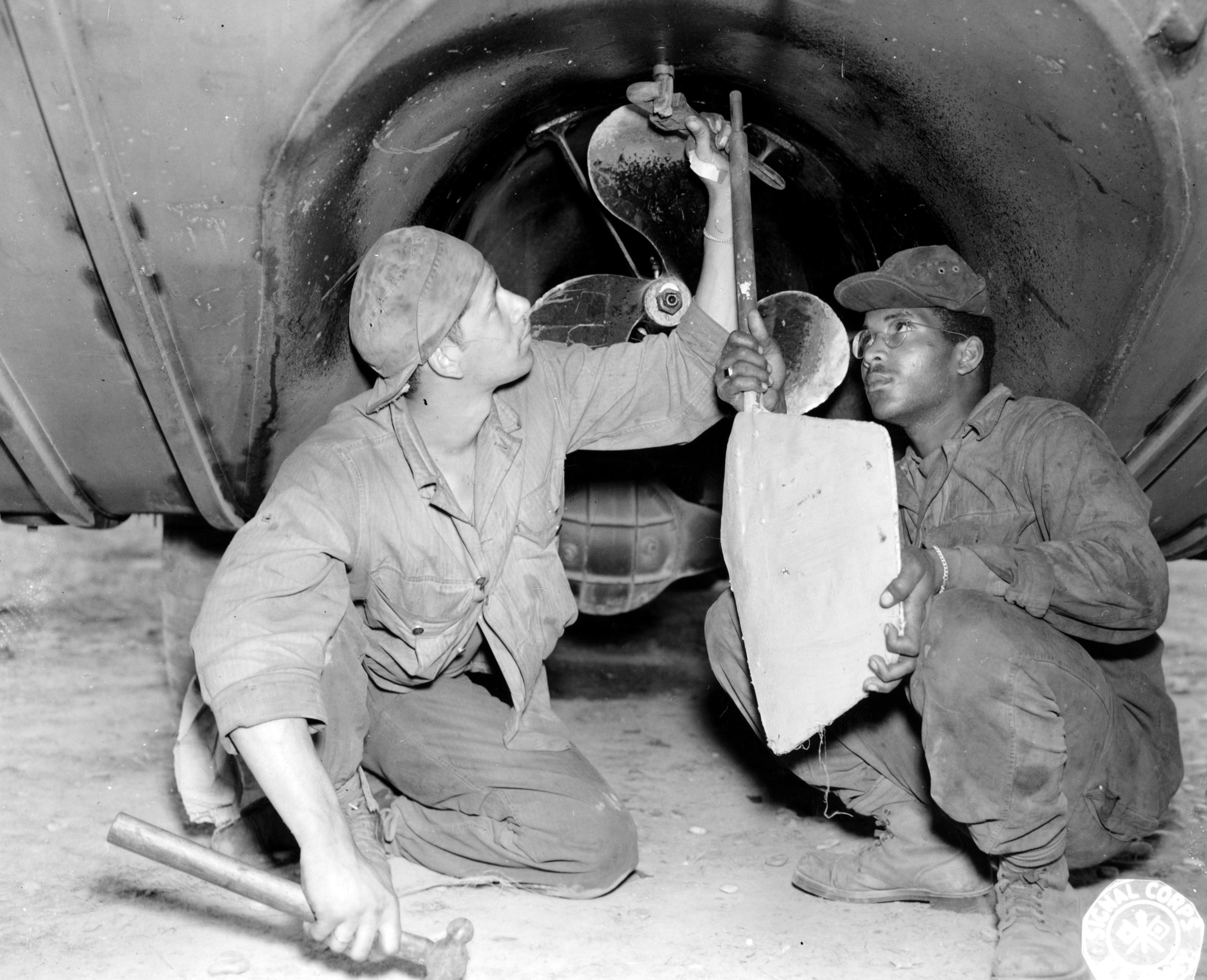 Historical image showing Corporal Oscar Adams and Corporal Floyd Carrio design an improvised rudder for DUKWs. of Black American soldiers during WWII