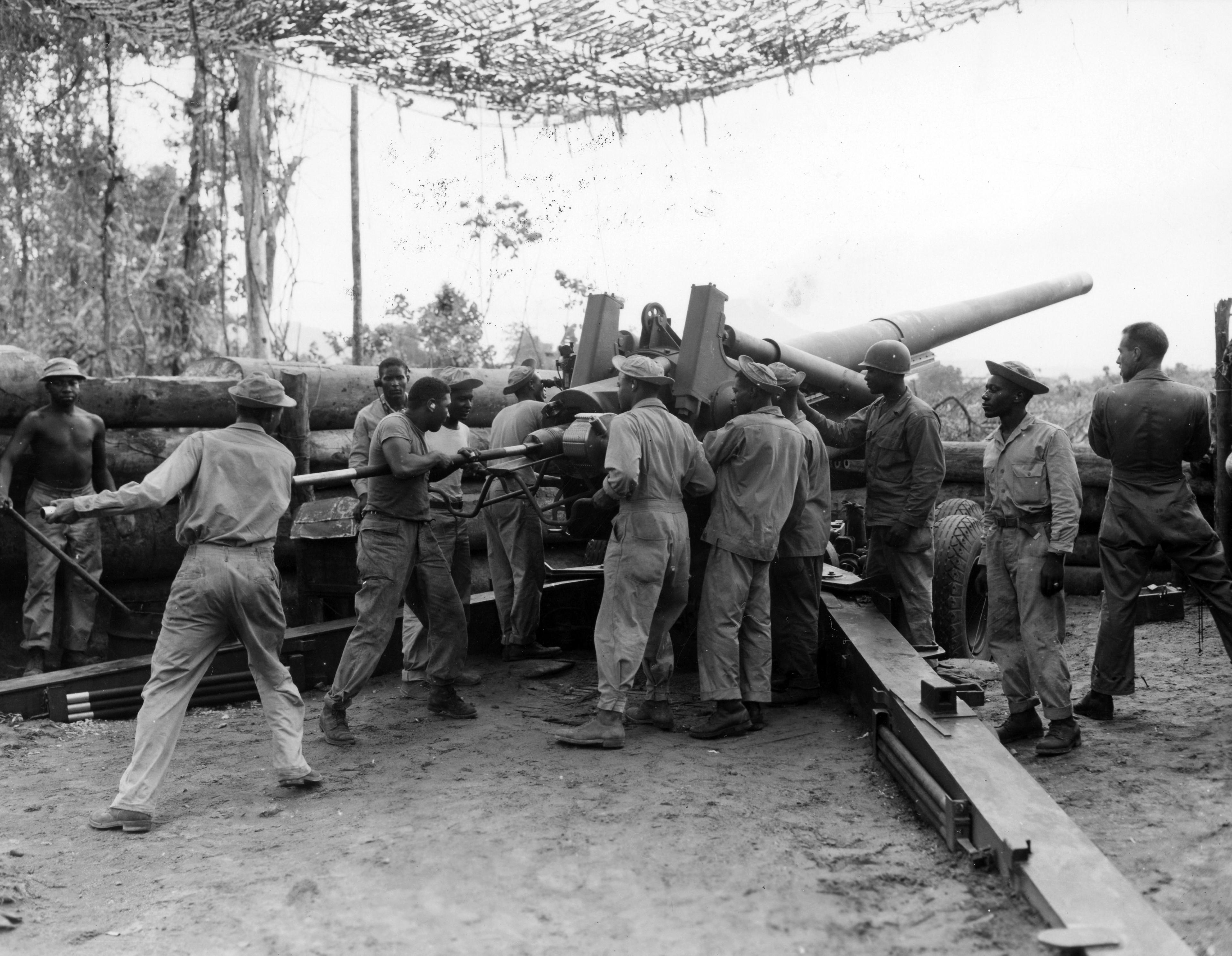 Historical image showing Members of the 49th Coast Artillery, (Colored) firing 155mm howitzer at night on Bougainville. of Black American soldiers during WWII