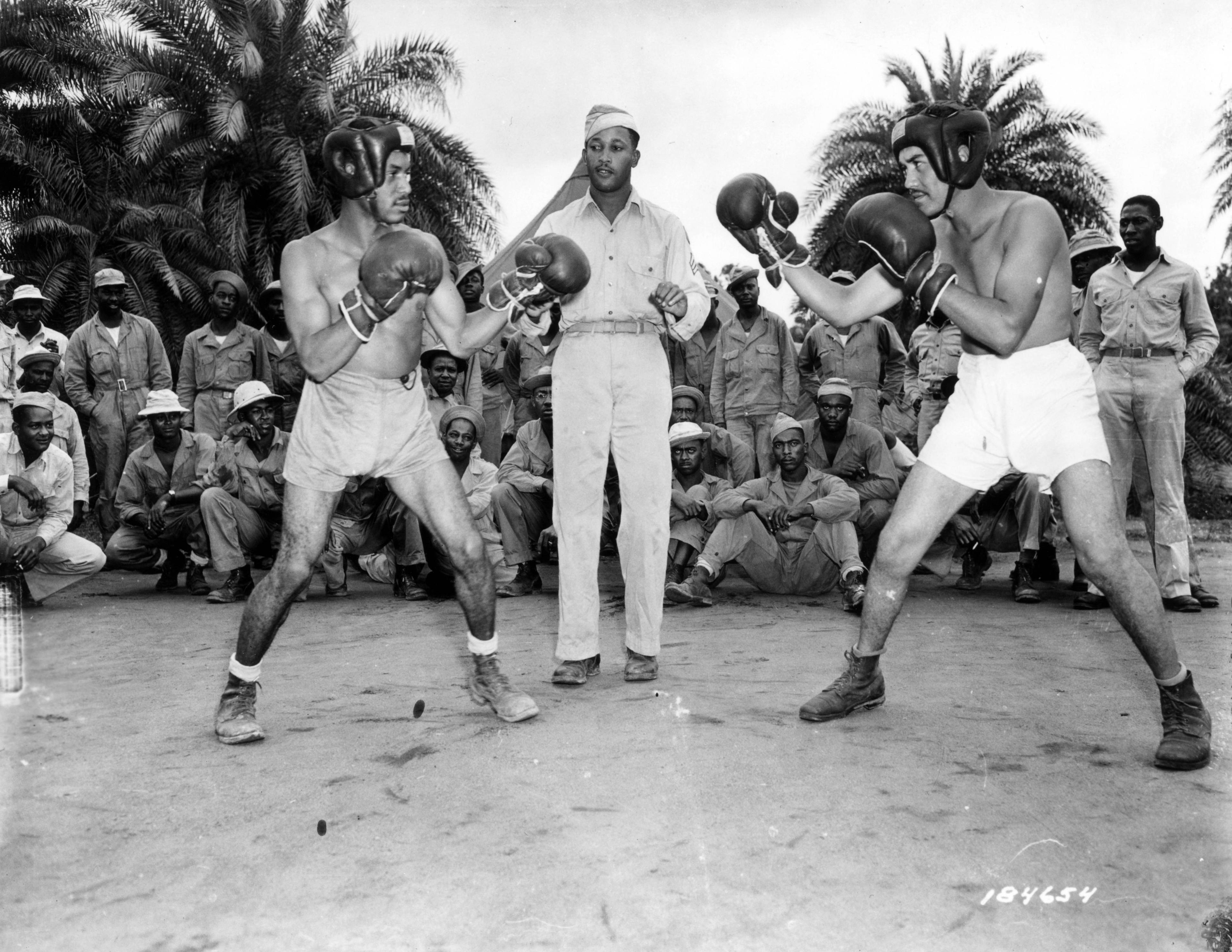 Historical image showing "Young Kid Usher" spars with Private First Class John D. Henry in a friendly boxing match. of Black American soldiers during WWII
