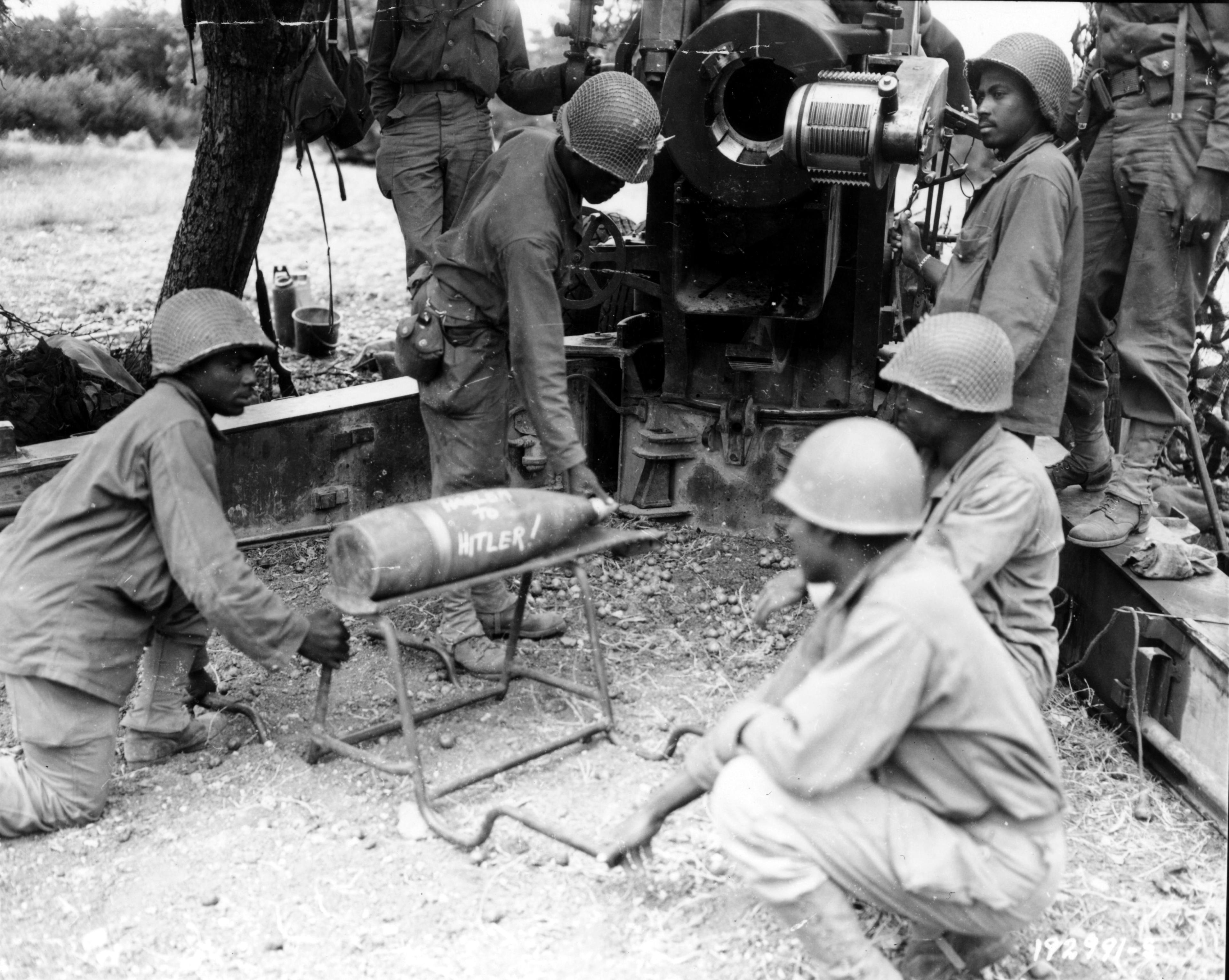 Historical image showing Another present from "Harlem to Hitler" is presented on behalf of an artillery outfit firing at German escape barges across the River Seine. of Black American soldiers during WWII