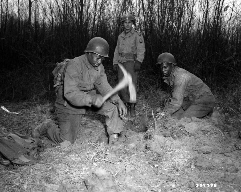 Historical image showing Private Felix Lawson and Private Sammie Jenkins dig a foxhole. of Black American soldiers during WWII